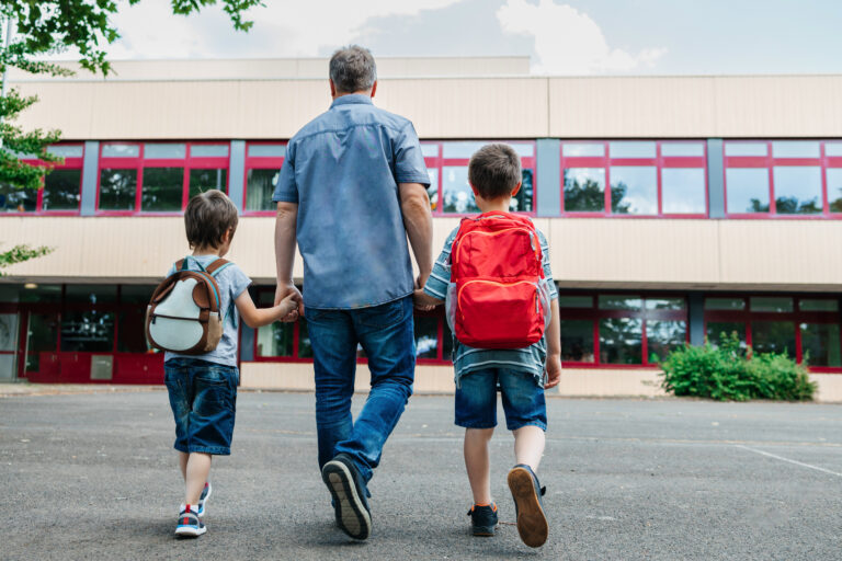 happy dad escorts his young kids to school.