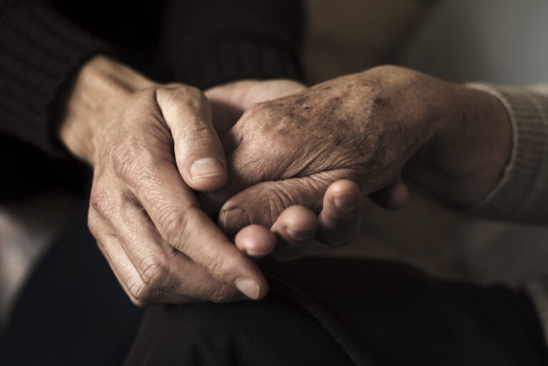 Closeup of young hands holding the hands of an elderly person