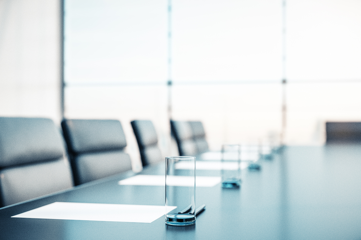 Close up of conference room with glasses of water on the table with papers, armchairs and a large window.