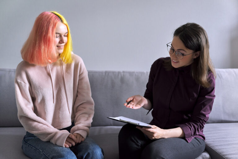 Teen girl and counsellor sitting on a couch talking