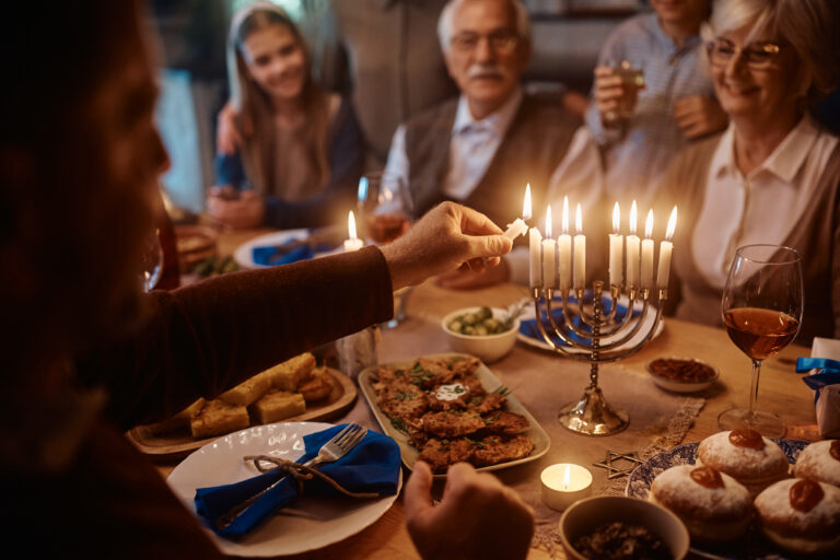 Close up of man lighting the menorah during family meal on Hanukkah.